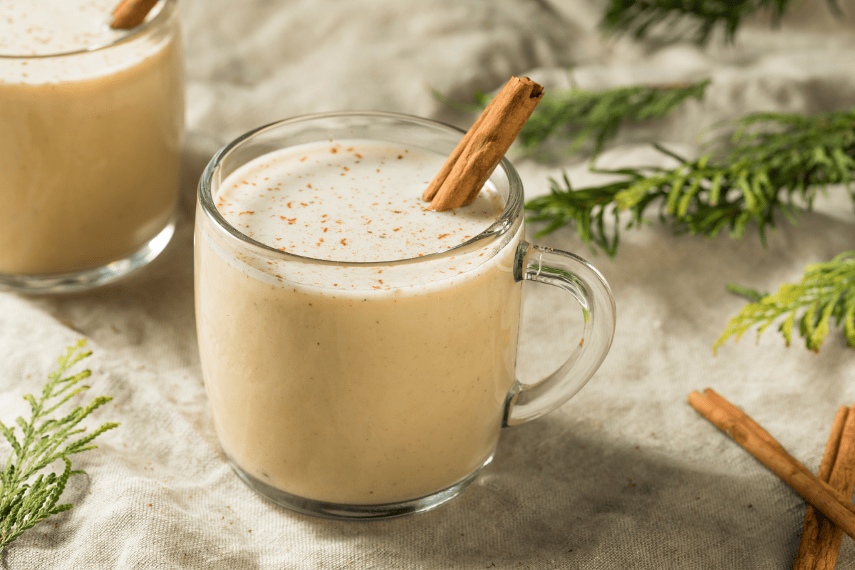 two glasses of eggnog garnished with cinnamon sticks