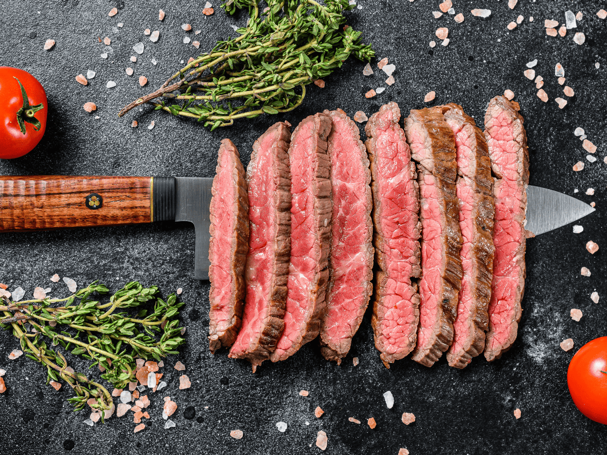 faldinha flap steak cooked rare and sliced with herbs and salt in the background