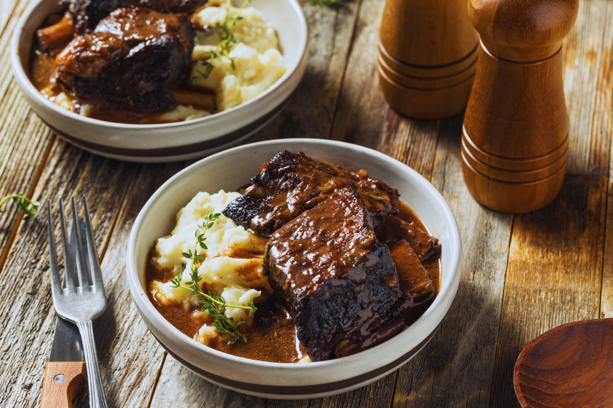braised beef short ribs in bowls over mashed potatoes